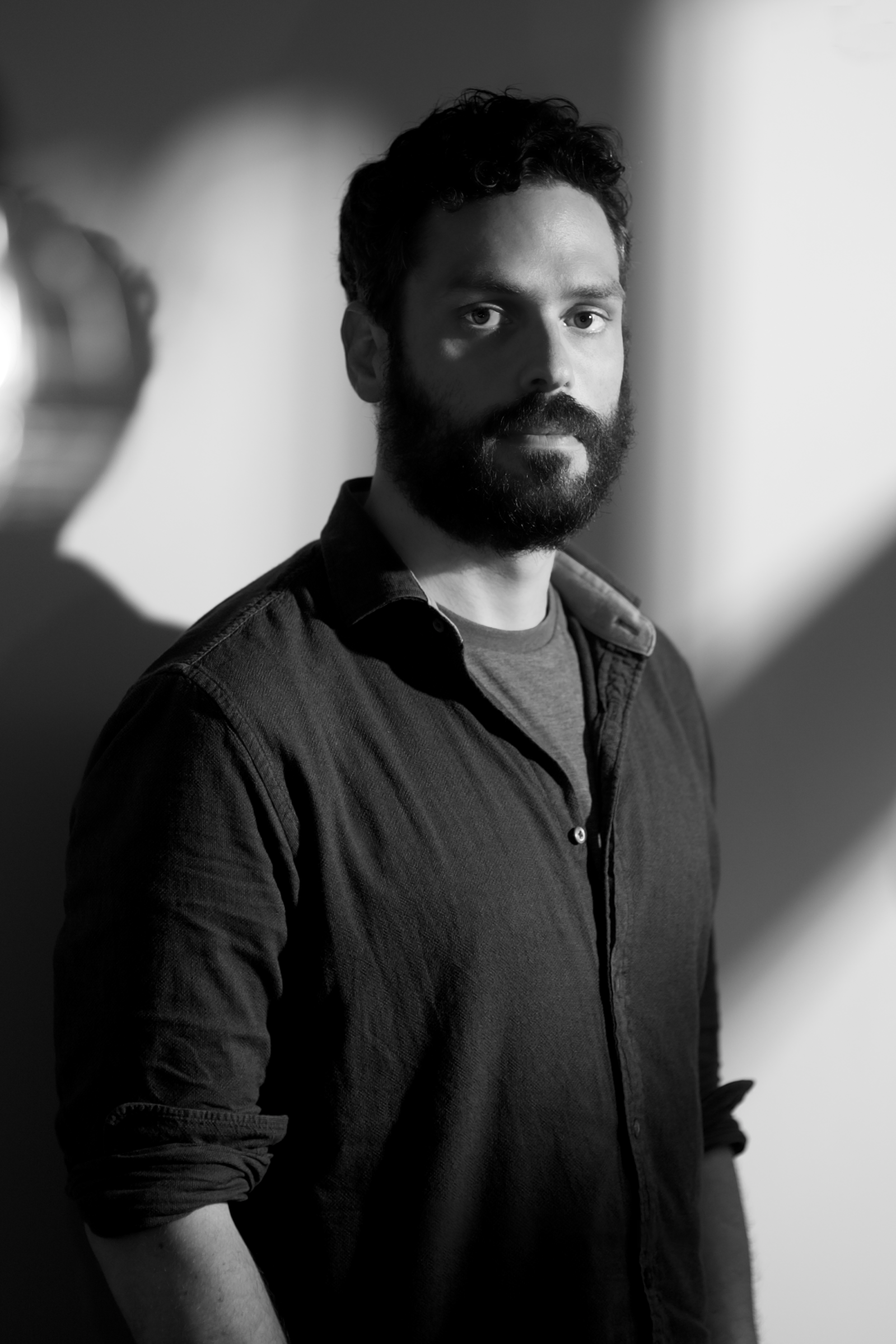 Contemporary artist Daan Olieroock in black and white standing in front of a neutral background. Photo by Kai Brethouwer